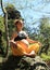 Pregnant woman sitting on stone in butterfly yoga pose