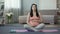 Pregnant woman sitting on yoga mat doing breathing exercises and massaging belly