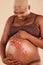 Pregnant woman, smile and flowers on stomach in studio, body and baby wellness of ivf healthcare. Mother, pregnancy and