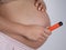 A pregnant woman smokes a vape. A girl holds an electronic cigarette against the background of her bare tummy.