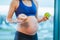 pregnant woman in sport suite with doughnut and apple near window day close up