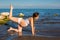 Pregnant woman in sports bra doing exercise in relaxation on yoga pose on sea