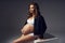 Pregnant woman in sports underwear sitting on large cube