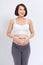 Pregnant woman standing and holding her hands in form of heart sign on her belly