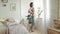 Pregnant woman standing near window. Belly mother stretching body at home.