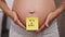 pregnant woman with a sticky note saying girl on her belly, closeup gender reveal concept