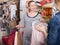 Pregnant woman in striped tunic communicates with seller in clothing store