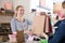 Pregnant woman in striped tunic communicates with seller in clothing store