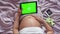 A pregnant woman strokes her stomach and holds a digital tablet with a chromakey. A pregnant girl with covered legs