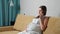 Pregnant woman talking on the phone experiencing contractions while sitting on the couch