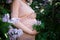 pregnant woman tenderly hugs her belly surrounded by lilac flowers