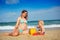 Pregnant woman and toddler play with sand on beach