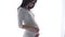 Pregnant Woman Touching Baby Belly In White Interior
