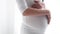 Pregnant Woman Touching Baby Belly In White Interior
