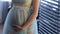 Pregnant woman in transparent clothes stands near wooden lattice