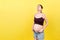 Pregnant woman in unzipped jeans showing her abdomen at colorful background with copy space