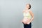 Pregnant woman in unzipped jeans showing her abdomen at colorful background with copy space