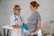 Pregnant woman visiting a doctor. Elderly Caucasian female gynecologist holds hands on the tummy of a pregnant patient.