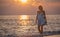 Pregnant woman is walking on the Maldivian beach during the sunrise
