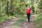 Pregnant woman walking in a summer forest using hiking poles