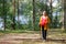 Pregnant woman walking in a summer forest using hiking poles
