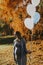 Pregnant woman walks in autumn park with balloons in hand