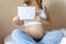Pregnant writing baby list. Beautiful pregnancy woman writing check list. Happy pregnant lady holding notepad. Pregnancy
