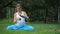 Pregnant yoga in the lotus position with thermos drinking tea. in the park on the grass , outdoor, health woman, female.