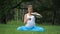 Pregnant yoga in the lotus position with thermos drinking tea. in the park on the grass , outdoor, health woman, female.