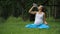 Pregnant yoga woman drinking water from a bottle, in the lotus position. park ,grass ,.outdoor, forest.