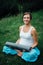 Pregnant yoga woman in the lotus position with mat portrait in park on the grass, breathing, stretching, statics.