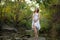 Pregnant young lady laughing holding 9 month expecting belly standing on creek bed in forest