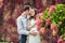 A pregnant young woman and her husband. A happy family standing at the red autumn hedge, smelling a flower hydrangea. pregnant