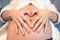 Pregnant young woman holding fingers in a heart shape