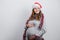Pregnant young woman in Santa hat smiling, touching her belly. Copy space. Christmas, New year concept.