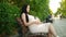 A pregnant young woman sits on a bench, affectionately caressing her pregnant belly, embodying a beautiful moment of