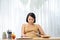 Pregnant young woman sitting and using digital tablet on table in living room and have a breakfast and working