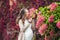 A pregnant young woman standing at the red autumn hedge, smelling a flower hydrangea. pregnant woman relaxing in the