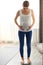 Pregnant young woman standing on scales at home. Pregnancy weight gain concept