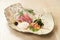 Premium Sashimi garnished with edible flowers in ceramic plate on wooden background