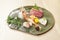 Premium Sashimi garnished with edible flowers in green ceramic plate on wooden background