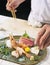 Premium Sashimi prepared by chef, Garnished with edible flowers in green ceramic plate on wooden background