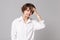 Preoccupied puzzled young business woman in white shirt posing isolated on grey wall background studio portrait