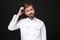 Preoccupied young bearded male chef cook or baker man in white uniform shirt posing isolated on black background studio
