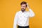 Preoccupied young bearded male chef cook or baker man in white uniform shirt posing isolated on yellow background in