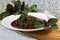 Prepaired braised amaranth - red spinach, in it`s own juce on white plate on wooden boarding