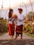 Preparation for Balinese ceremony. Multicultural couple preparing for Hindu religious ceremony with god`s offerings. Penjor bambo