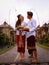 Preparation for Balinese ceremony. Multicultural couple preparing for Hindu religious ceremony with god`s offerings. Penjor bambo