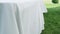 Preparation of a banquet on a green lawn. The wind develops a light green tablecloth