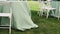 Preparation of a banquet on a green lawn. The wind develops a light green tablecloth.